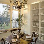 Nad stołem wisi elegancki żyrandol. Rezydencja strojna w antyki