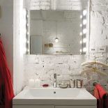 Nad umywalką wisi lustro oświetlone żarówkami.