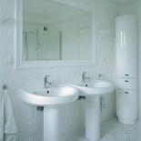 Nad umywalkami wisi lustro. Dom w bieli i błękicie