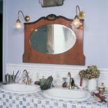 Nad umywalkami wisi lustro w drewnianej ramie.