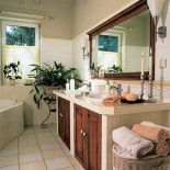 Nad umywalkami wisi lustro w drewnianej ramie.