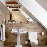 Naturalne kolory i materiały sprawiają, że łazienka gospodarzy jest przytulna. Nawet glazura fakturą przypomina drewno.