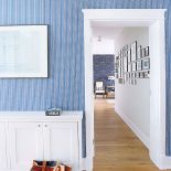 Niebieska tapeta w delikatne biało-granatowe paseczki nadaje wnętrzom morskiego klimatu.