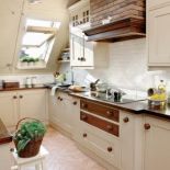 Nietypowe, duże uchwyty szafek, dwukolorowe szuflady i ceglany okap sprawiają, że kuchnia wygląda ciekawie.