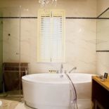 Nowoczesność miesza się z klasyką: czarną mozaikę i przezroczyste krzeslo Philippe a Starck a zestawiono z chłodnymi