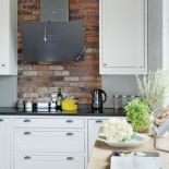 Nowoczesny okap, proste szafki kuchenne i tradycyjnie wypalana holenderska cegła.