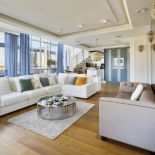 W SALONIE: DĘBOWA PODŁOGA Z ETSSO. SOFA PIKOWANA, STOLIK KAWOWY I KINKIETY MARKI EICHHOLTZ. BIAŁA NAROŻNA SOFA – OLTA.