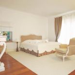 Obok łóżka stoi wygodny fotel. Prostota i naturalność