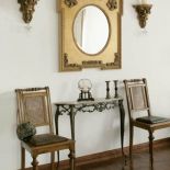 Obok lustra wiszą rzeźbione świeczniki.