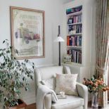 Obok regału stoi jasny fotel. Róże i falbanki