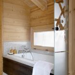 Obudowę wanny zrobiono z takiego samego bejcowanego drewna jak szafki pod umywalką i obudowano granitem.