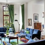 otwarta przestrzeń, wielkie okna. Światło wpada do salonu z czterech stron i aż lśni na tkaninach.