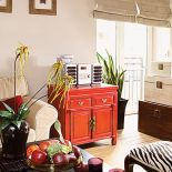 Ozdobą salonu jest czerwona szafka, na której stoi sprzęt rtv.