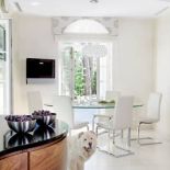 Pełen światla i lekkośći kuchenny kącik na małe co nieco. Biel, szkło i chrom. Szklany blat stołu zdaje się