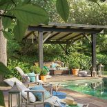 Pod zadaszeniem ustawiono wygodne kanapy sporo dekoracji roslinnych.