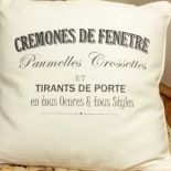 Poduszka uszyta z bawełnianej tkaniny w kolorze jasnego kremu. Przednia strona ozdobiona czarnym nadrukiem francuskiej