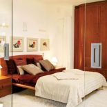 Poduszki na łóżku uzupełniają się kolorystyką ze ścianami i meblami.