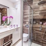 Połączenie imitacji drewna z przeszkleniami dodaje łazience nowoczesnego charakteru.