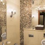 Półokrągłe kąty niewielkiej łazienki wyłożono szklaną mozaiką.