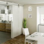 Pomysł do niewielkiego mieszkania - przesuwane szklane drzwi odgradzają kuchnię od jadalni, ale nie zajmują miejsca. HAFELE