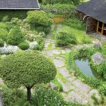 Poszczególne części ogrodu wyznaczają ścieżki: na podjeździe wokół klombu z tujami i jałowcami ułożona została