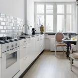 Proste szafki z białymi frontami w towarzystwkie antycznego stołu i krzeseł.