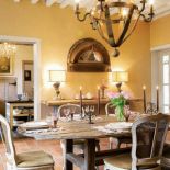 Prosty drewniany stół i zdobione krzesła.