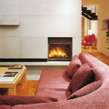 Przed minimalistycznym kominkiem mozna się rozsiąść w na wygodnej kanapie.