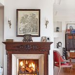 Przy kominku stoi wiktoriański fotel wyaptrzony na targu.