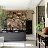 Przytulny salon z biblioteką i teatralnymi dekoracjami.