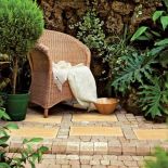 Ratanowy fotel idealnie pasuje do kostki w piaskowym kolorze. Aranżacja LIBET