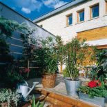 Rośliny w donicach sprawiają wrażenie, że taras i ogród przenikają się.