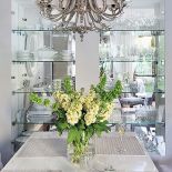 Rozświetlona szklanymi witrynami, a także lustrem i bogatym żyrandolem od Eichholtza. Elegancki stół pochodzi z