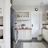 Rustykalna elegancja z pałacową posadzką i lodówką glamour. Do tego ciepłe drewno i swojskie ceramiczne