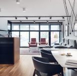 Salon umeblowano w proste meble. Pomieszczenie doświetla naturalne światło wpadające przez loftowe okna.