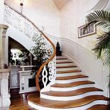 Schody z litego drewna wykończone półokrągłymi stopniami. Balustrada z kutego żelaza. PRACOWNIA SCHODÓW PAZURA