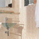 Ściana wyłożona jest trawertynem Moka (cena około 500 zł/mkw.), obok kremowa mozaika Travertino Beige (5 x 5 x 1