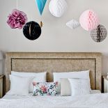 Ściany w perłowym różu i papierowe ozdoby pod sufitem.