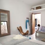 Skórzany dizajnerski fotel i wielkie lustro oparte o ścianę.