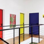 Śnieżnobiałe ściany i wielokolorowe drzwi aż fosforyzują barwą.