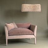 Sofka w pudrowym różu z puchatą lampą.