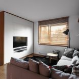 Strefa telewizyjno-wypoczynkowa, a w niej narożna szara kanapa z miękkimi poduszkami.