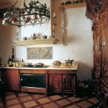 Stylizowane na stare komody szafki kuchenne przykryto kamiennym blatem. Gzyms komina jest z piaskowca.