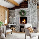 Surowe ściany z drewna i szary, kamienny kominek podgrzano finezyjnym detalem.