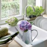 Świeże zioła w doniczkach na parapecie i warzywa i kwaty hortensji - ulubienicy pani domu.