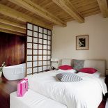 Sypialnia jest oddzielona od łazienki delikatnym przepierzeniem zrobionym z drewna i matowego szkła.
