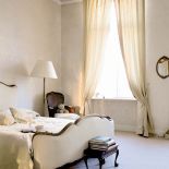 Sypialnia pani i pana domu urządzona jest w ciepłych odcieniach ecru.