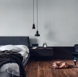 Sypialnia urządzona jest minimalistycznie. Nowoczesny charakter podkreślają wiszące na długich kablach lampy, spełniające