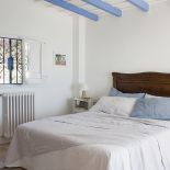 Sypialnia z błękitnymi drewnianymi belkami pod sufitem.