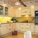 Szafki kuchenne w prowansalskim stylu z uchwytami z ceramicznymi wstawkami. Na ścianie i podłodze żyłkowany kamień.